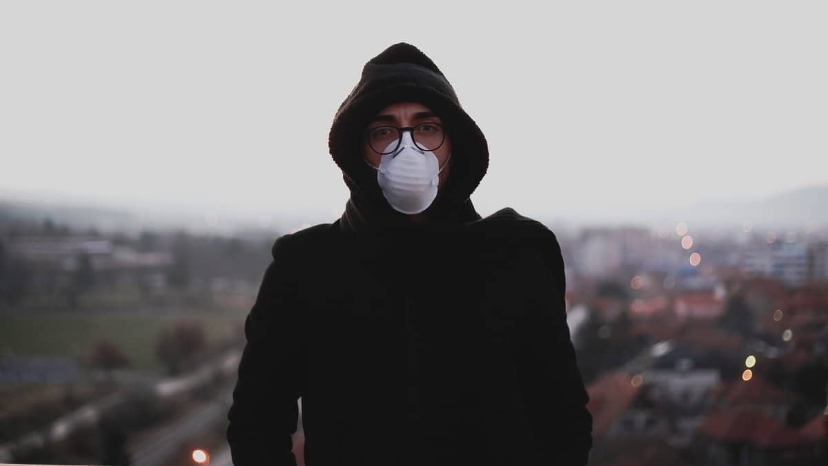 A man with surgical mask standing on a polluted street