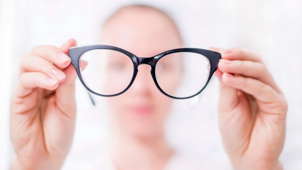 A woman holding her glasses close to the camera