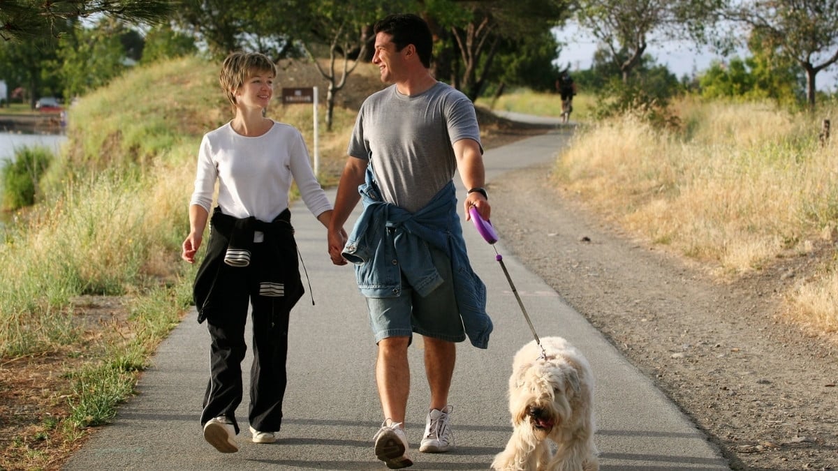 A young couple walking together in park with dog