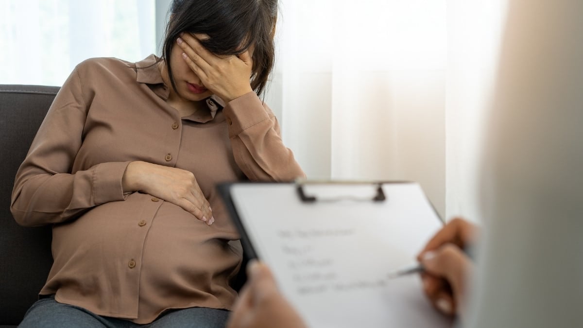a stressed pregnant woman sits with a therapist