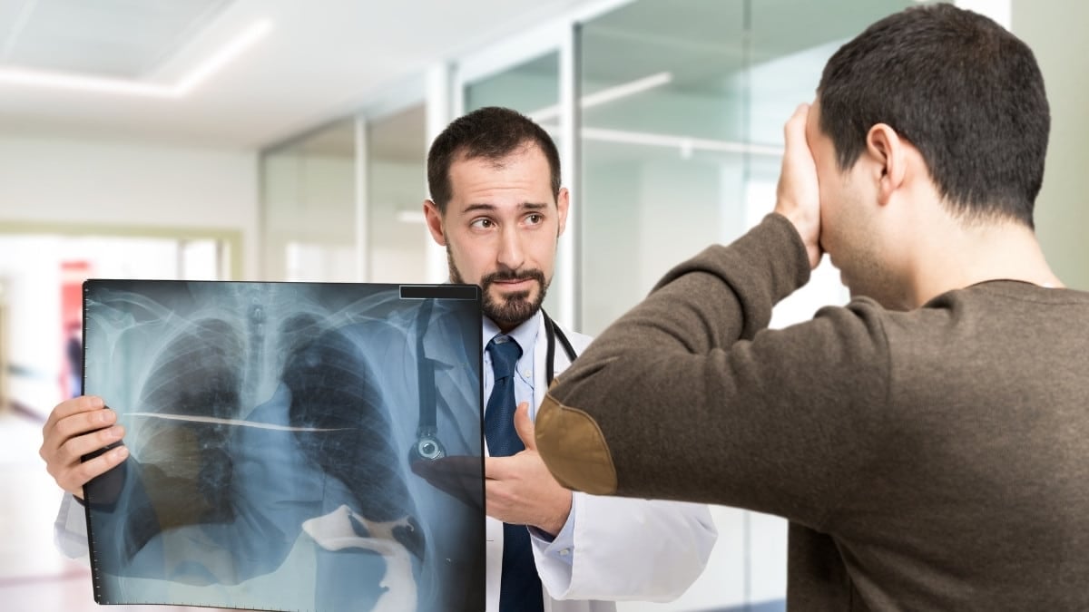 doctor holding an x-ray report informs patient of lung cancer