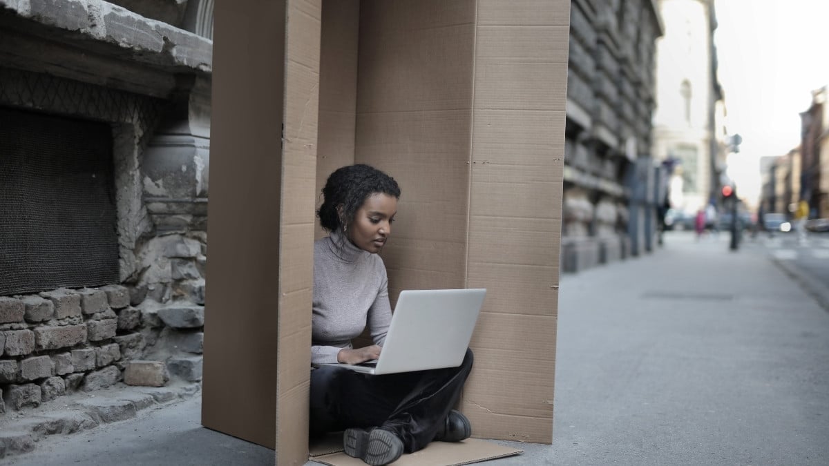 woman sitting with her laptop in a box on the street