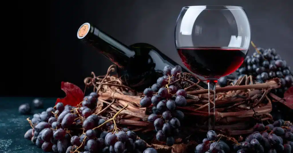 bottle of wine, grapes and a glass lying on a table