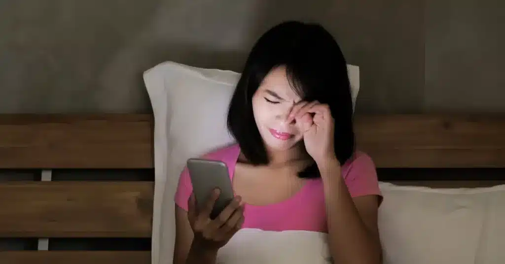 A female rubbing her eye in a dim mobile light