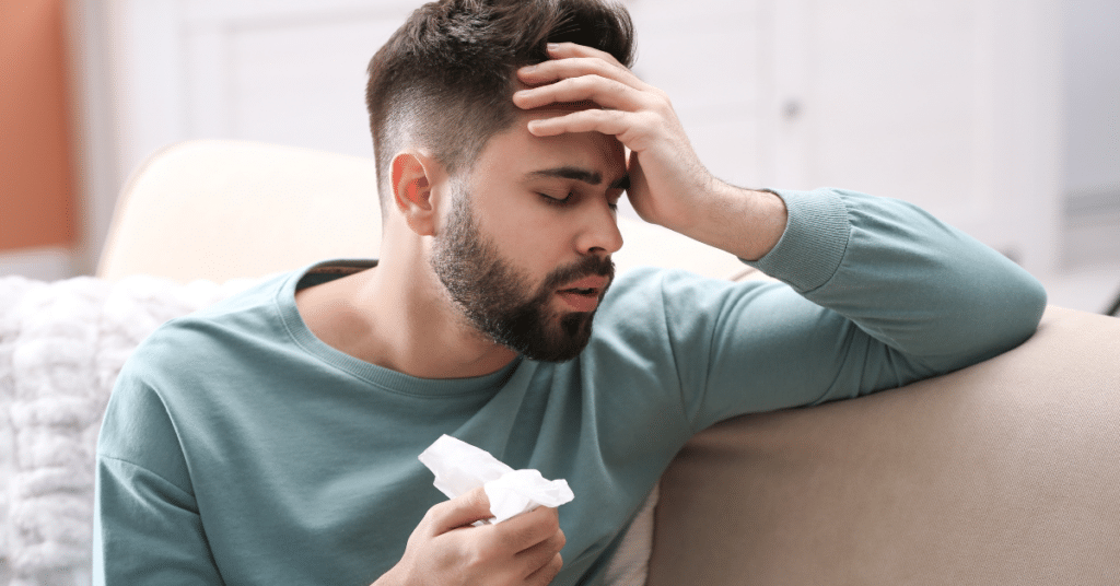 Man resting his hand on his forehead because of fever