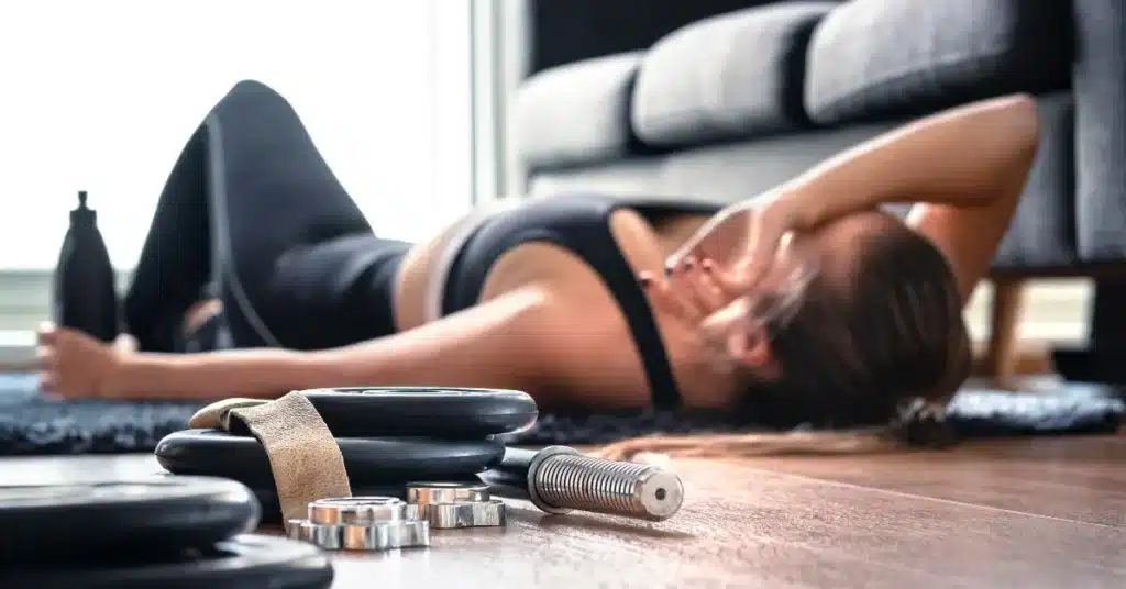 a tired woman laying on the floor due to excessive exercise